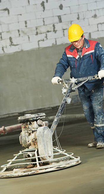 Worker trowelling and finishing of concrete by special construction equipment